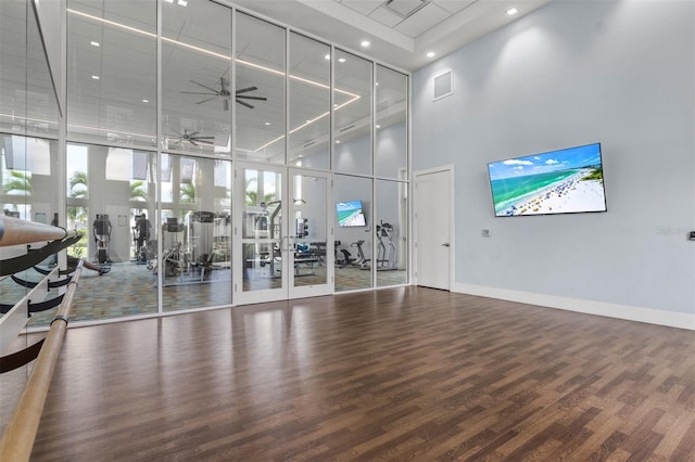 exercise room featuring a wall of windows, dark wood-type flooring, and a high ceiling