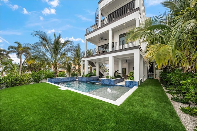 rear view of house with ceiling fan, a yard, pool water feature, a balcony, and a patio area