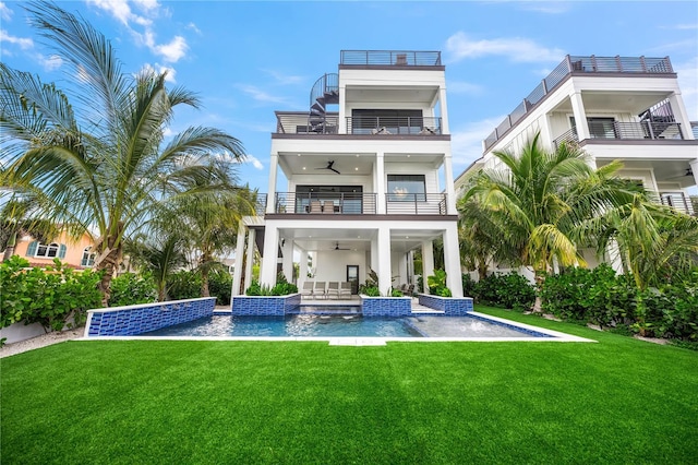 back of property with a swimming pool with hot tub, ceiling fan, a balcony, and a lawn