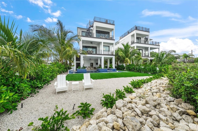 back of house featuring an outdoor hangout area, a balcony, ceiling fan, a patio area, and a lawn