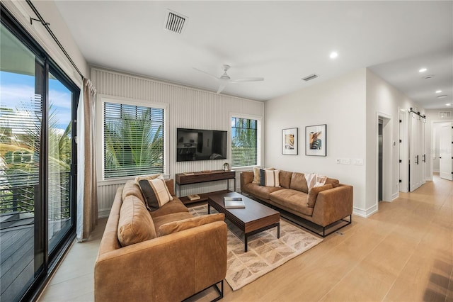 living room with a barn door and ceiling fan