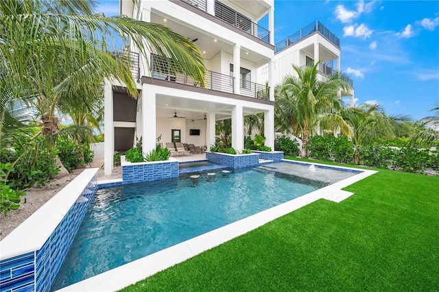 view of swimming pool featuring a lawn, ceiling fan, a patio, and pool water feature