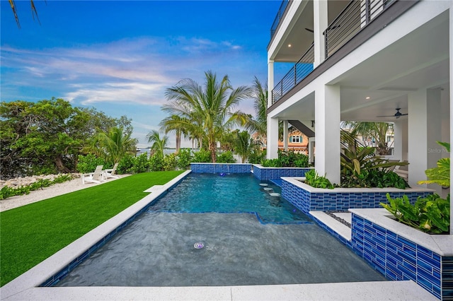 view of swimming pool with a lawn, ceiling fan, and pool water feature