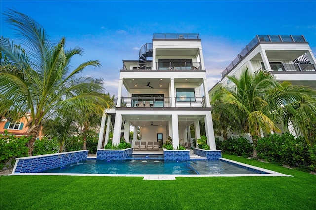 back of property with a yard, a balcony, ceiling fan, and a patio area