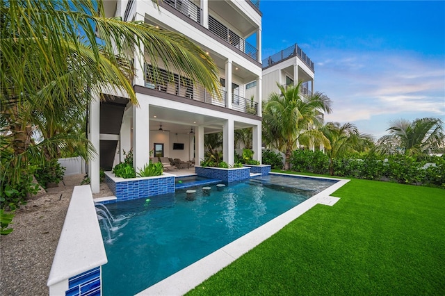 back of house featuring a lawn, pool water feature, ceiling fan, a balcony, and a patio