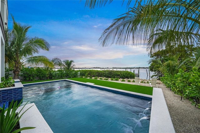 view of pool featuring a water view and a yard