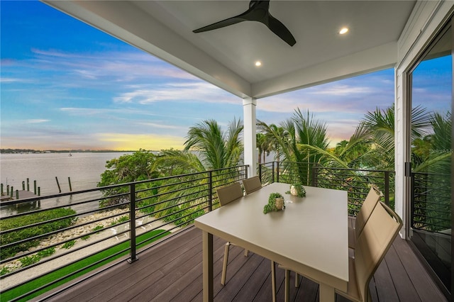 balcony at dusk with ceiling fan and a water view