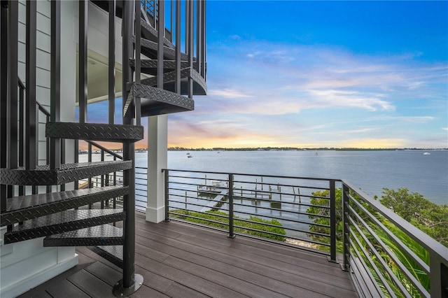 deck at dusk featuring a water view