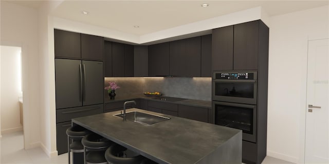 kitchen featuring sink, stainless steel appliances, an island with sink, a kitchen bar, and light tile patterned floors