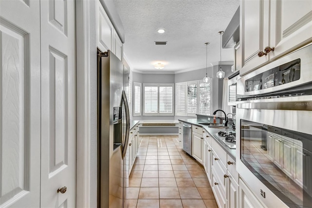 kitchen featuring pendant lighting, a textured ceiling, stainless steel appliances, and white cabinets