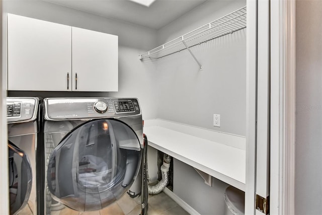 laundry area with cabinets, light tile patterned floors, and washing machine and clothes dryer