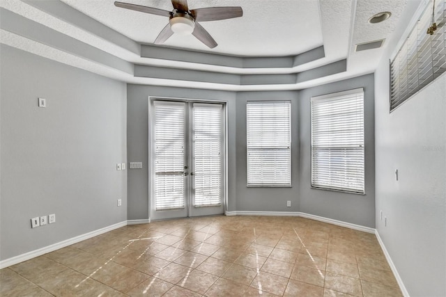 spare room featuring ceiling fan, a tray ceiling, a textured ceiling, light tile patterned flooring, and french doors