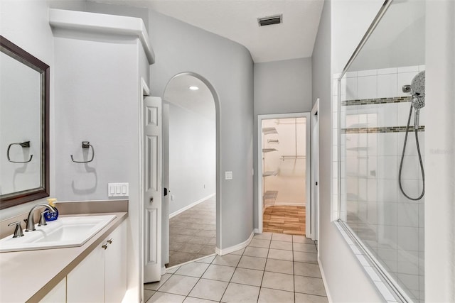 bathroom with tiled shower, vanity, and tile patterned flooring