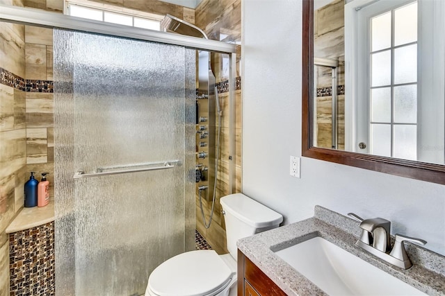 bathroom featuring vanity, toilet, and a shower with shower door