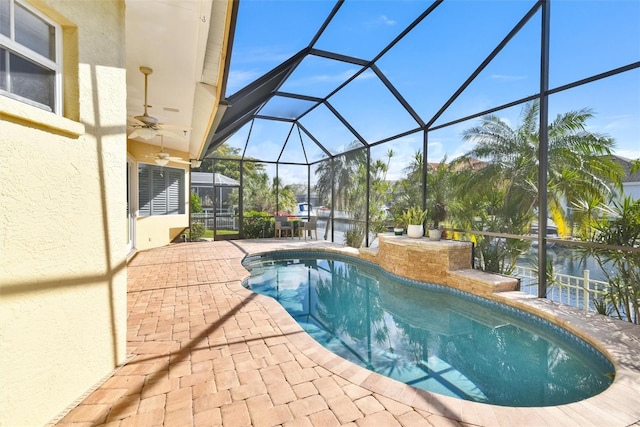 view of pool featuring ceiling fan, a water view, glass enclosure, and a patio