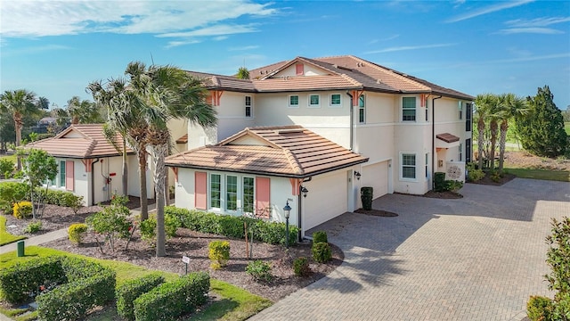 view of front of home featuring an attached garage, stucco siding, decorative driveway, and a tiled roof