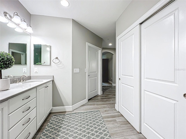 bathroom featuring wood tiled floor, vanity, baseboards, and recessed lighting