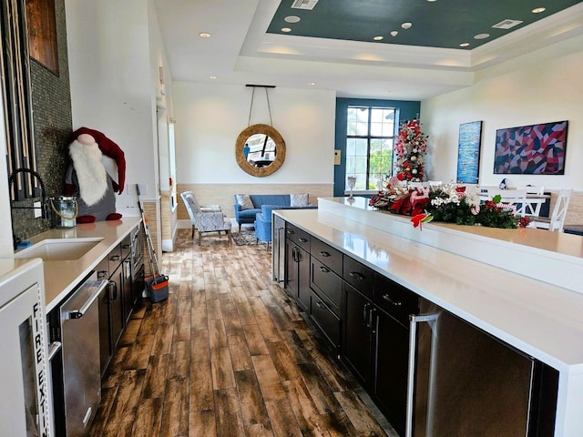 kitchen with open floor plan, dark wood-type flooring, a raised ceiling, and dark cabinets