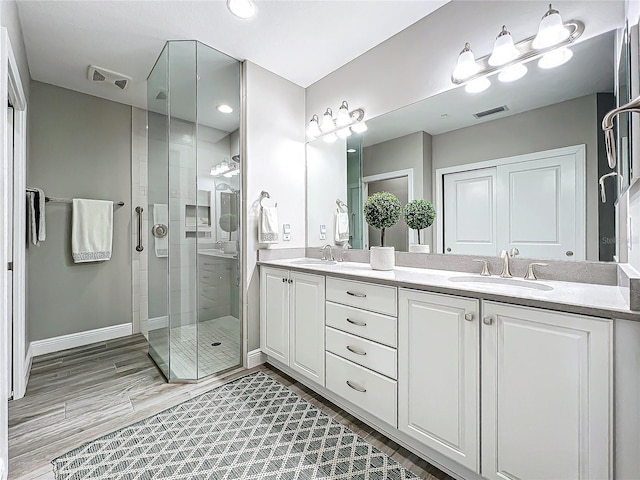 bathroom featuring visible vents, a sink, a shower stall, and double vanity