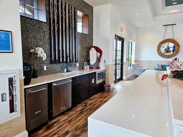 bar featuring dark wood-style floors, appliances with stainless steel finishes, backsplash, and a sink