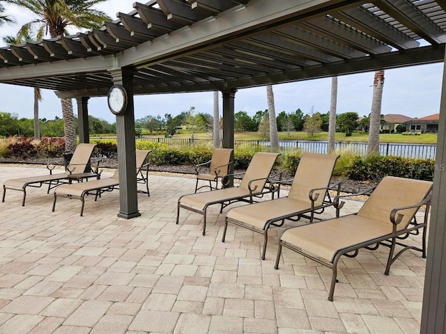 view of patio with a water view, fence, and a pergola