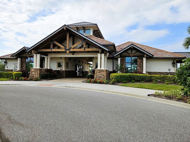 craftsman house featuring stone siding, a tiled roof, and stucco siding