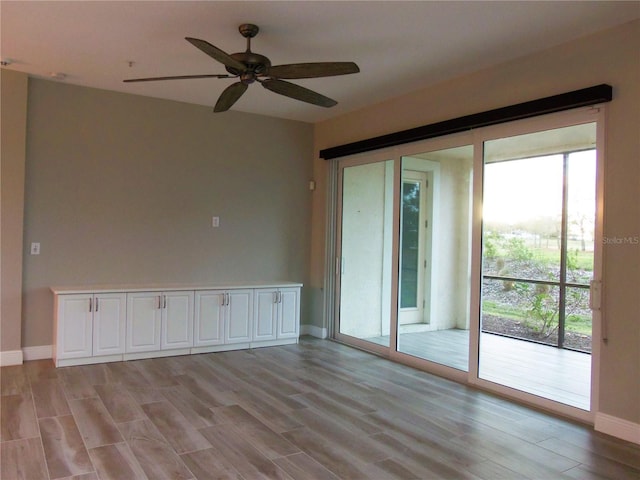 spare room with baseboards, a ceiling fan, and light wood-style floors