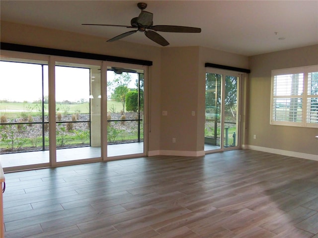 spare room featuring wood finished floors, a ceiling fan, and baseboards