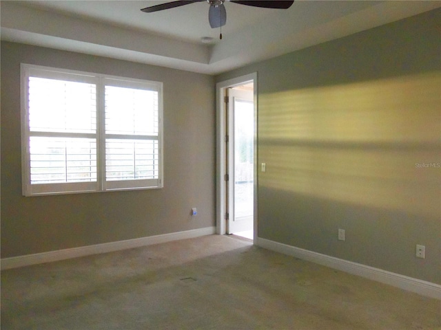 carpeted spare room featuring ceiling fan and baseboards