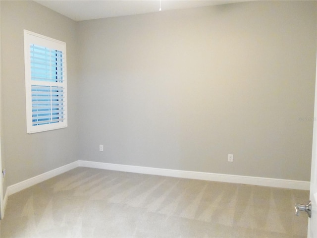 empty room featuring light carpet and baseboards