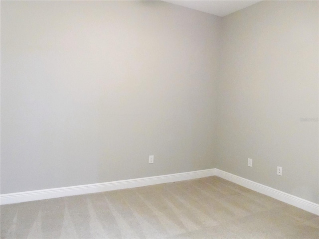 empty room featuring light carpet and baseboards