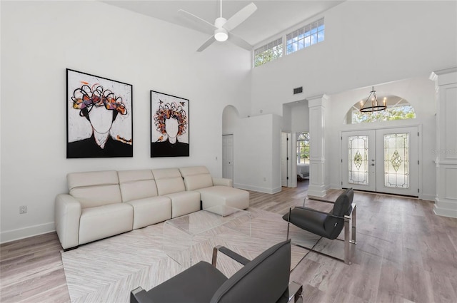 living room with plenty of natural light, decorative columns, and light wood-type flooring