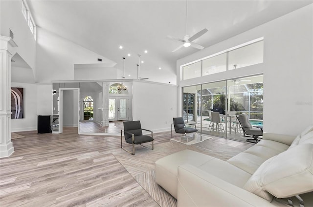 living room featuring ornate columns, a towering ceiling, ceiling fan, light wood-type flooring, and french doors