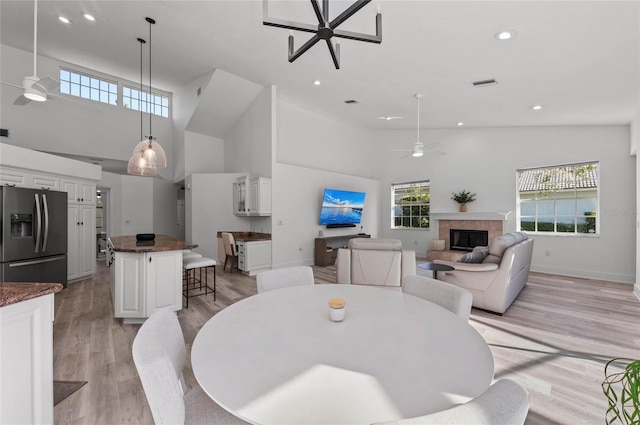 dining room featuring ceiling fan, plenty of natural light, and a tiled fireplace