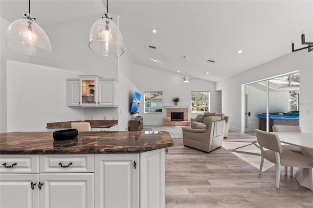 kitchen featuring hanging light fixtures, white cabinetry, and a tiled fireplace