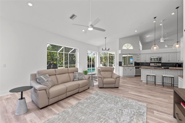 living room featuring ceiling fan, high vaulted ceiling, and light hardwood / wood-style floors