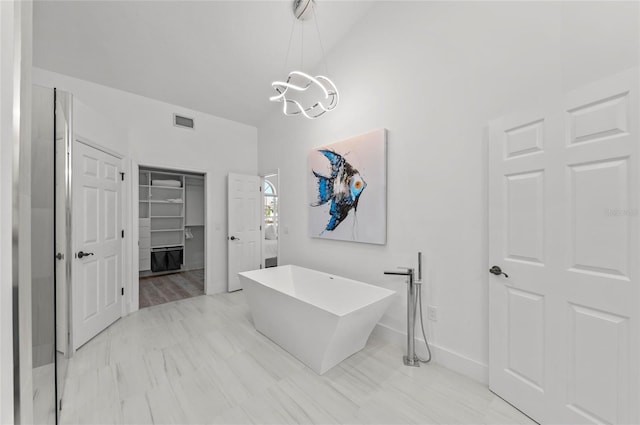 bathroom featuring an inviting chandelier, high vaulted ceiling, and a tub