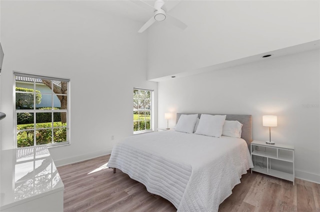 bedroom with a towering ceiling, light hardwood / wood-style flooring, and ceiling fan