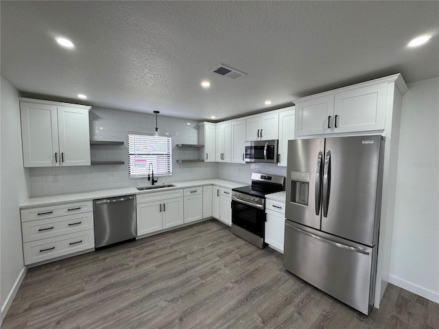 kitchen featuring sink, hanging light fixtures, dark wood-type flooring, stainless steel appliances, and white cabinets