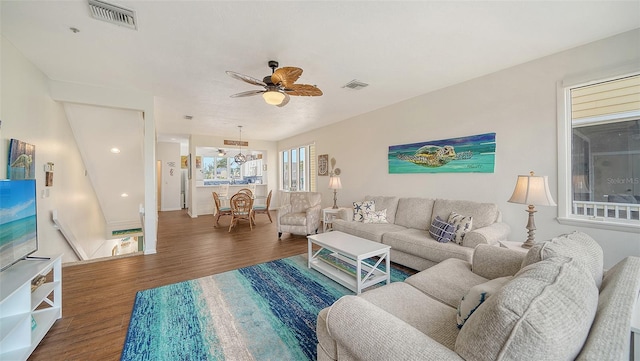 living area with ceiling fan, visible vents, and wood finished floors