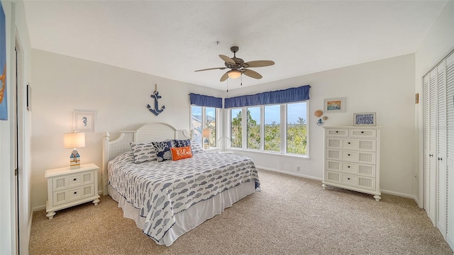 bedroom with light carpet, a ceiling fan, baseboards, and a closet