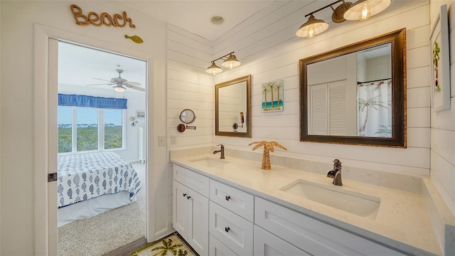 full bathroom with double vanity, wood walls, a sink, and connected bathroom