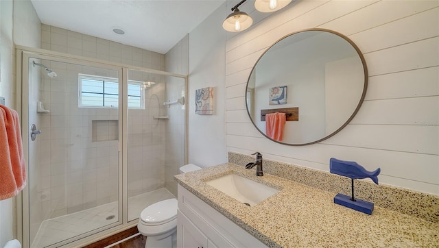 bathroom with toilet, a stall shower, wooden walls, and vanity