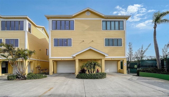 view of front of property with stucco siding, a garage, fence, and driveway