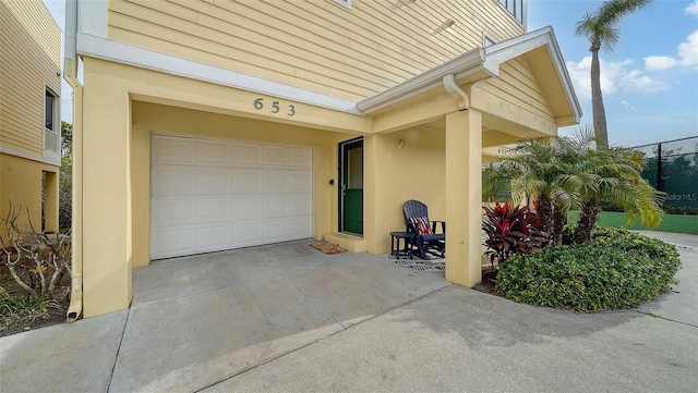 doorway to property with concrete driveway, a garage, and stucco siding