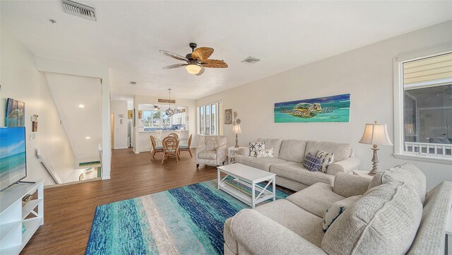living area featuring ceiling fan with notable chandelier, wood finished floors, and visible vents
