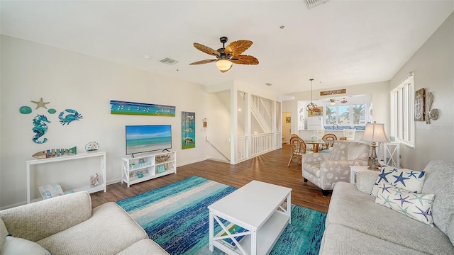 living area featuring visible vents, baseboards, ceiling fan, and wood finished floors