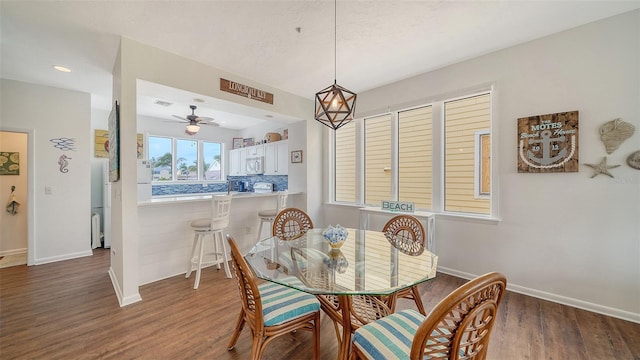dining space with a ceiling fan, baseboards, and wood finished floors