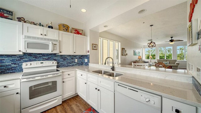 kitchen with dark wood-style flooring, tasteful backsplash, a sink, white appliances, and white cabinetry