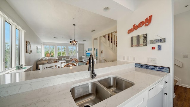 kitchen featuring light stone countertops, white dishwasher, white cabinets, a sink, and dark wood finished floors